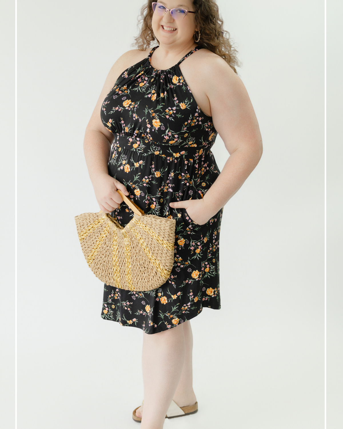 Woman wearing a black floral dress holding a beaded handbag on a white background | Model Photo - Emily | Harlow + James Boutique | West Des Moines, IA