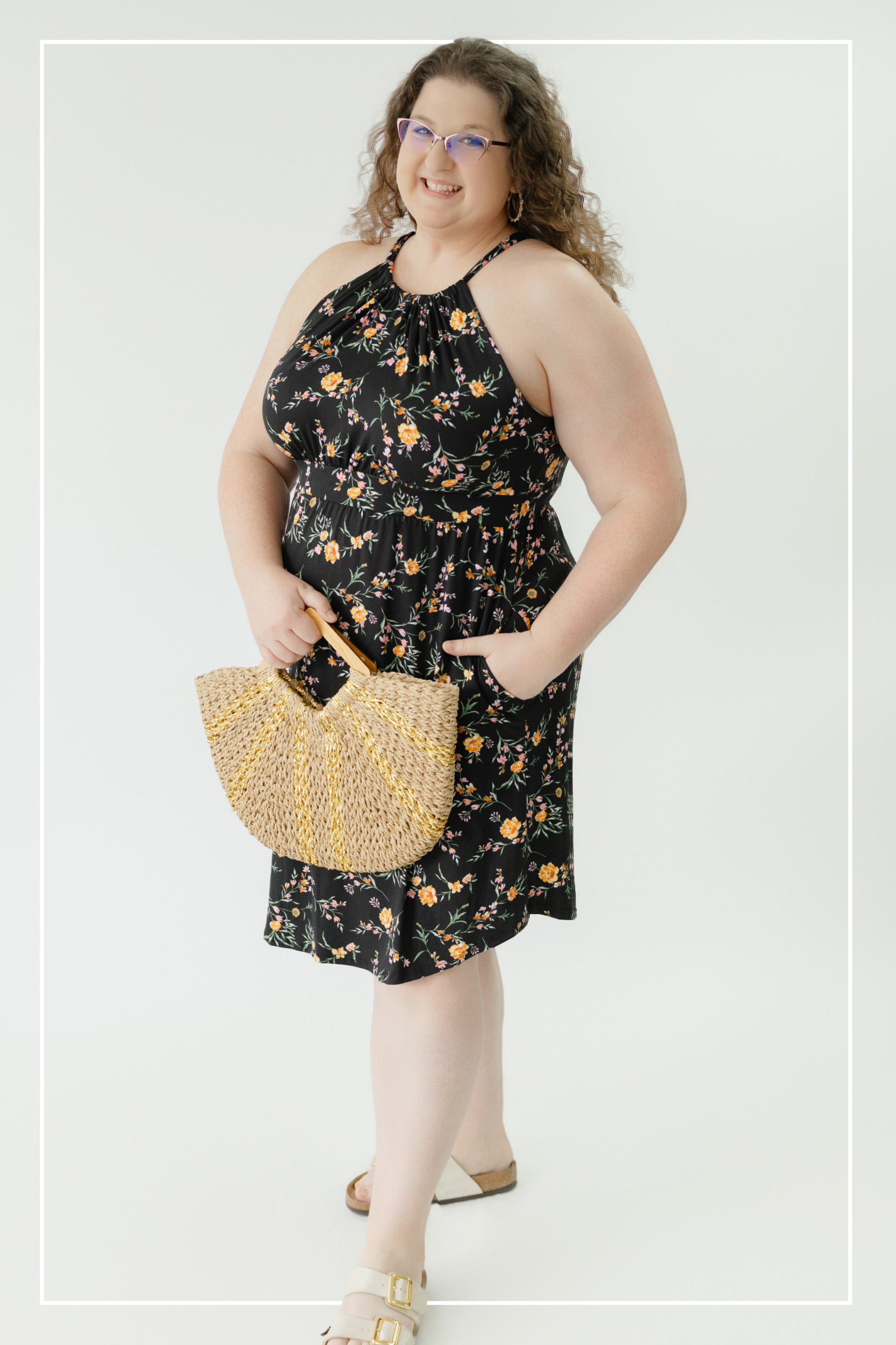 Woman wearing a black floral dress holding a beaded handbag on a white background | Model Photo - Emily | Harlow + James Boutique | West Des Moines, IA