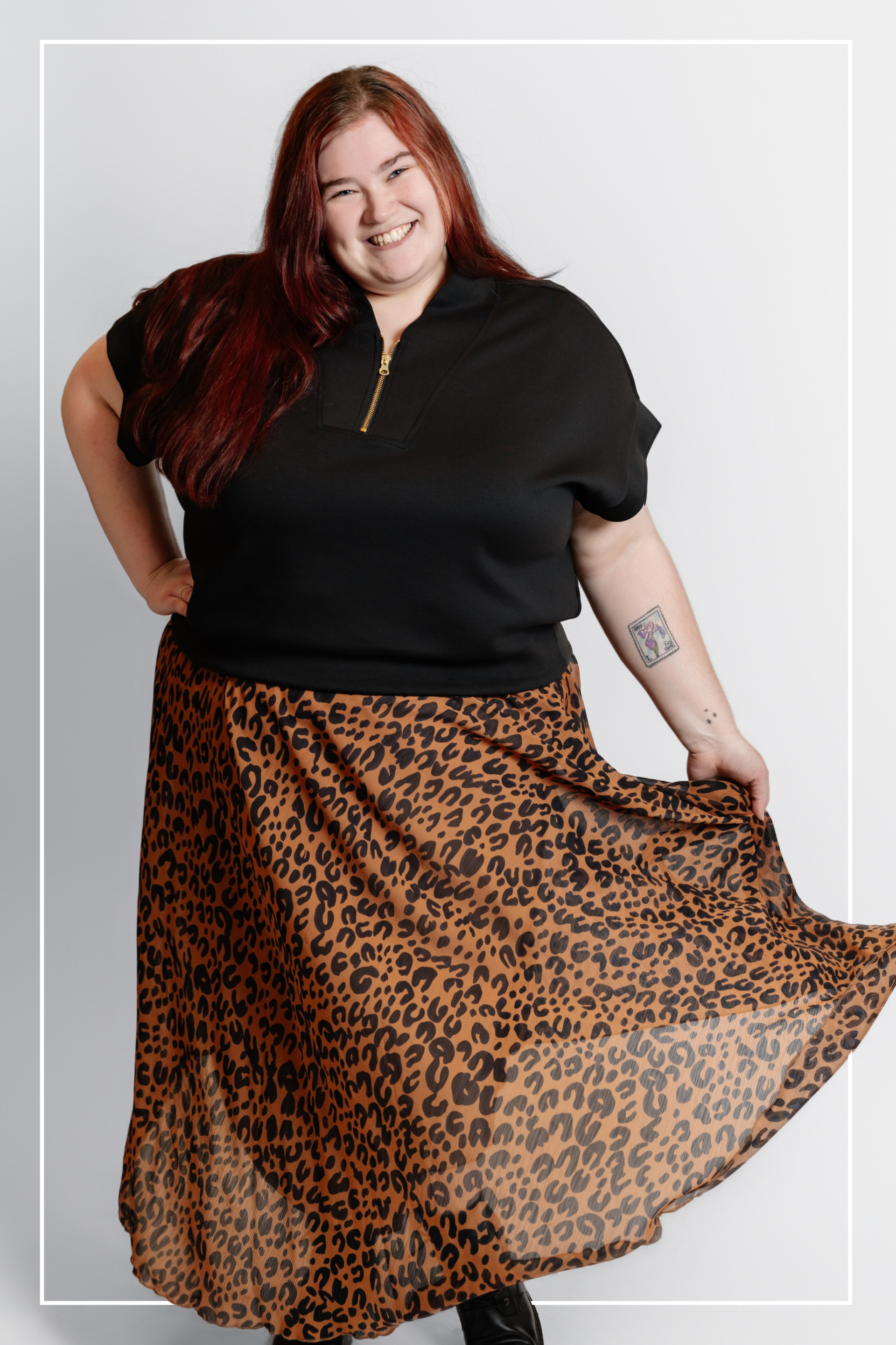 Person wearing a black top and leopard print skirt on a plain background | Model Photo - Cora Jane | Harlow + James Boutique | West Des Moines, IA