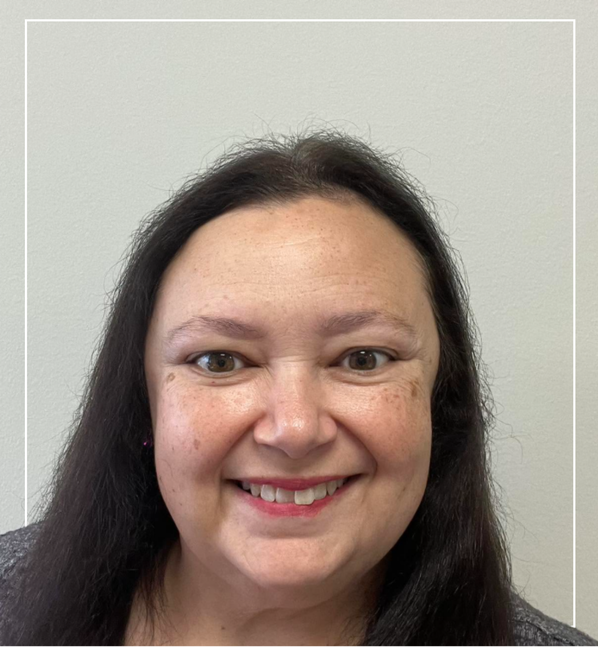Woman with long dark hair smiling against a plain background | Staff - April | Harlow + James Boutique | West Des Moines, IA