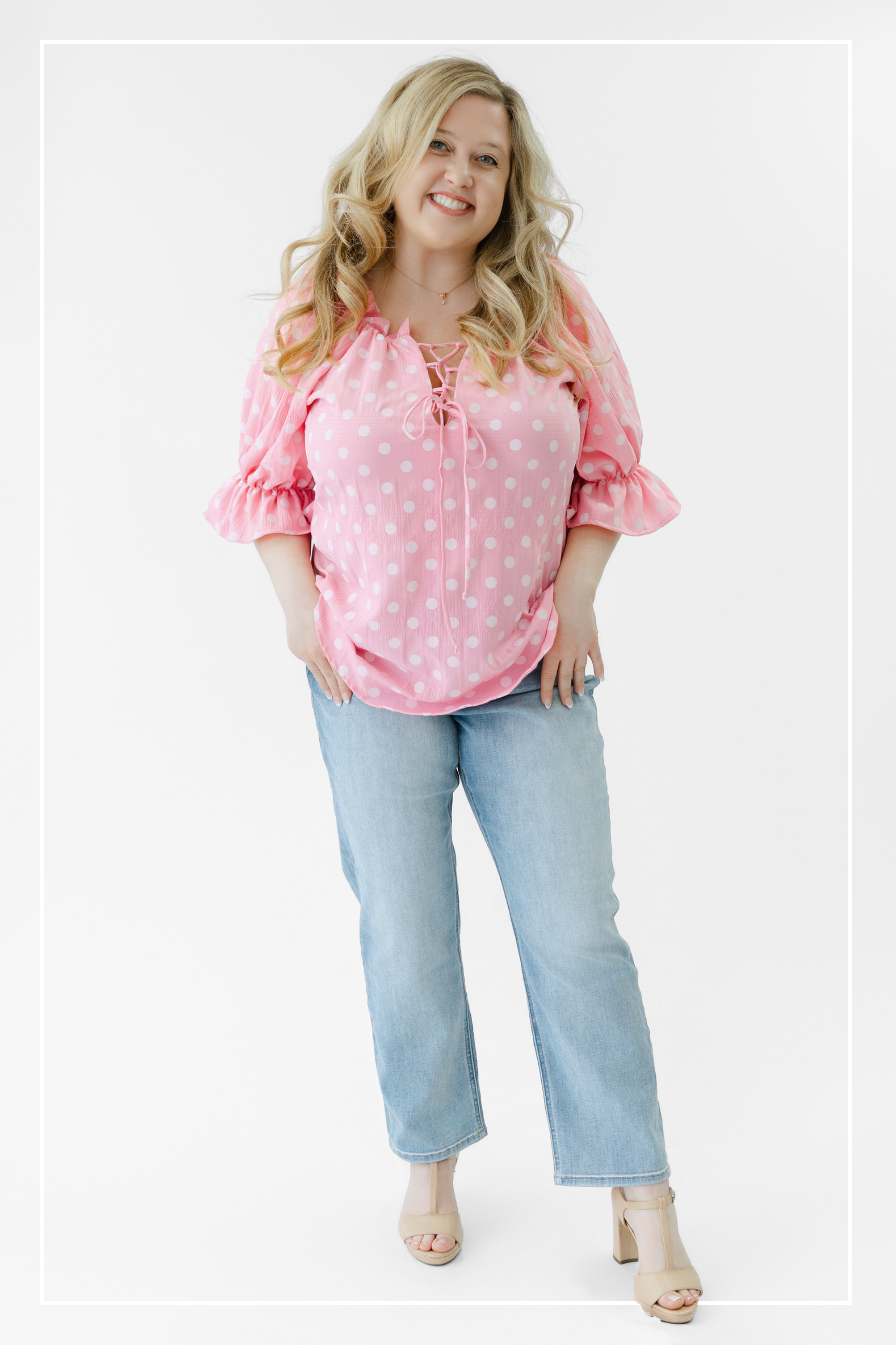 Woman wearing a pink polka dot blouse and light blue jeans on a white background | Model Photo - Kaitlyn | Harlow + James Boutique | West Des Moines, IA